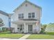 Charming two-story white home featuring a cozy front porch with seating and a well-manicured lawn at 107 Amaranth Ave, Summerville, SC 29483