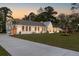 Well-lit single-story home with a long driveway, manicured lawn, and crisp white painted brick exterior at 1183 Farm Quarter Rd, Mount Pleasant, SC 29464