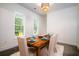 Bright dining room with a rustic wood table set for a meal and scenic backyard view through windows at 1183 Guerins Bridge Rd, Awendaw, SC 29429