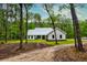 Farmhouse as seen from the tree-lined driveway; lush green lawn and manicured landscaping at 1183 Guerins Bridge Rd, Awendaw, SC 29429