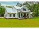 Charming farmhouse featuring a metal roof, covered front porch, and lush green lawn at 1183 Guerins Bridge Rd, Awendaw, SC 29429