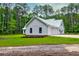 The side exterior view of the farmhouse shows the three car garage and manicured landscaping at 1183 Guerins Bridge Rd, Awendaw, SC 29429