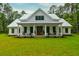 Inviting two-story farmhouse with a metal roof and a covered front porch, with verdant green front lawn at 1183 Guerins Bridge Rd, Awendaw, SC 29429