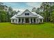 Beautiful two-story farmhouse with a metal roof and a covered front porch, set on a verdant lawn at 1183 Guerins Bridge Rd, Awendaw, SC 29429