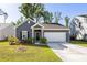 Charming single-story home featuring a two-car garage, manicured lawn, and a welcoming entrance at 1411 Thin Pine Dr, Johns Island, SC 29455