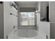 A bathtub with tiled walls, decorative shelving, and a window with privacy blinds at 177 Sugar Magnolia Way, Charleston, SC 29414
