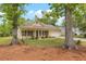 A cozy home framed by mature trees, featuring a well-kept lawn, front porch, shutters, and an attached garage at 1953 Suzanne St, Johns Island, SC 29455