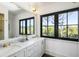 Elegant bathroom featuring double sinks, marble countertops, and black frame windows at 20 Old Cedar Ln, Kiawah Island, SC 29455
