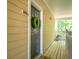 A welcoming exterior view of a unit door with a green wreath, number 302, and a covered porch with a wooden floor at 200 Bucksley Ln # 302, Charleston, SC 29492