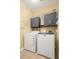 This laundry room has gray cabinets, wire racks, and white washer and dryer at 200 Bucksley Ln # 302, Charleston, SC 29492