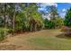A lush backyard featuring healthy grass, mature trees, and a wooden deck on a sunny day at 2524 Deer Walk Way, Mount Pleasant, SC 29466