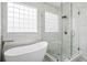 Bright bathroom with a stylish soaking tub and glass shower, enhanced by white marble-style tiles and unique block windows at 3526 Stockton Dr, Mount Pleasant, SC 29466