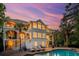 Beautiful multi-story home featuring private balconies, a serene pool, and well-manicured grounds at dusk at 4952 Steeplechase Ln, Hollywood, SC 29449
