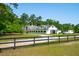 Spacious horse barn with white exterior and black accents surrounded by green pastures at 4952 Steeplechase Ln, Hollywood, SC 29449