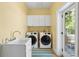 Bright laundry room with washer, dryer, utility sink, cabinets, and outdoor access to the porch at 4952 Steeplechase Ln, Hollywood, SC 29449
