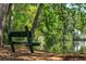 Scenic view of a green wooden park bench beside a pond surrounded by lush trees at 4952 Steeplechase Ln, Hollywood, SC 29449
