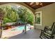View of a swimming pool and deck from a covered wooden porch with rocking chairs at 4952 Steeplechase Ln, Hollywood, SC 29449
