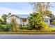 A quaint white brick house featuring a metal roof surrounded by lush greenery and palms at 561 Seaward Dr, Charleston, SC 29412