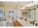 Bright bathroom with double sinks, bathtub, shower, and balcony access into the main bedroom at 68 W 9Th St # B, Folly Beach, SC 29439