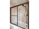 A tub-shower with a tile surround, black-framed sliding glass door, and niche at 68 W 9Th St # B, Folly Beach, SC 29439