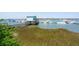 Waterfront marina view with a blue building on stilts, a wooden walkway, and numerous boats at 68 W 9Th St # B, Folly Beach, SC 29439