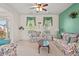 Cozy living room featuring floral sofas, a ceiling fan, and natural light from two large windows at 8956 N Red Maple Cir, Summerville, SC 29485