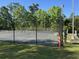 Community tennis court surrounded by a black fence and lush green trees at 104 Huntington Cir, Summerville, SC 29485