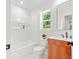 Modern bathroom boasts white tile, wooden vanity, and a window with leafy views at 1049 Bradford Ave, Charleston, SC 29412