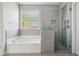 Modern bathroom with a shower and soaking tub, glass block window for natural light, and gray tile at 1409 Endicot Way, Mount Pleasant, SC 29466