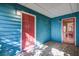 Covered blue wood porch with a red front door and storm door to the interior dining room with a view of the kitchen at 1417 Pine Island View, Mount Pleasant, SC 29464