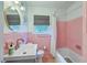 Pink tiled bathroom featuring vintage fixtures, a shower-tub, and a classic vanity at 1421 Fairfield Ave, Charleston, SC 29407