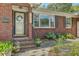 Inviting front porch area showcasing a decorated glass door, brick accents, and vibrant landscaping for added charm at 1421 Fairfield Ave, Charleston, SC 29407