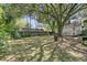 Spacious backyard with large shady tree, fire pit, partial fence and home exterior in background at 1450 E Montague Ave, North Charleston, SC 29405