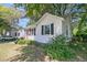 Quaint home with a pink front door, black shutters, green bushes, and a detached garage at 1450 E Montague Ave, North Charleston, SC 29405