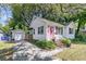 Cozy home with a pink door, a paved driveway, and a detached garage surrounded by lush landscaping at 1450 E Montague Ave, North Charleston, SC 29405