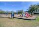 A colorful playground set surrounded by wood chips, grass, and lush foliage at 1450 E Montague Ave, North Charleston, SC 29405