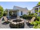 Backyard featuring a stone fire pit with Adirondack chairs, a covered patio, and well-maintained landscaping at 1526 Old Rivers Gate Rd, Mount Pleasant, SC 29466