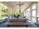 Relaxing screened-in porch with a farmhouse table, chandelier, and lots of natural light at 1526 Old Rivers Gate Rd, Mount Pleasant, SC 29466