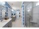 Well-lit bathroom with blue bamboo wallpaper, double vanities, and a glass-enclosed shower featuring a built-in seat at 1562 Charming Nancy Rd, Charleston, SC 29412