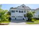Charming two-story white home boasts a three-car garage, manicured lawn and classic design elements at 1562 Charming Nancy Rd, Charleston, SC 29412