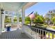 Charming front porch with white railings and columns, American flag, and views of the neighborhood street and landscaping at 1659 Pierce St, Daniel Island, SC 29492