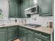 Well-equipped kitchen with dark green cabinets, granite countertops, stainless steel appliances, and a subway tile backsplash at 1828 S James Gregarie Rd, Mount Pleasant, SC 29466