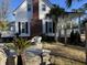 Charming home featuring a brick chimney, white siding, and a welcoming front porch surrounded by lush palm trees at 2001 Baltusrol Ct, Summerville, SC 29483