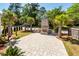 Paver patio with brick outdoor fireplace surrounded by green tropical landscaping at 2001 Baltusrol Ct, Summerville, SC 29483
