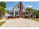 White home featuring a brick chimney and landscaped patio with palm trees and a seating area at 2001 Baltusrol Ct, Summerville, SC 29483