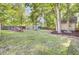 Beautifully landscaped backyard with mature trees, a cozy shed, and inviting seating around a fire pit area at 2021 Beckton St, North Charleston, SC 29420