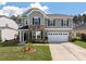 Two-story home with stone accents, white garage door, and well manicured lawn at 210 Witch Hazel St, Summerville, SC 29486