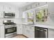 This updated kitchen features stainless appliances, sleek white cabinets, and a bright window over the sink at 238 Howle Ave, Charleston, SC 29412
