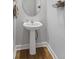 Elegant powder room featuring a pedestal sink, oval mirror, and rustic decor on wood-look flooring at 245 Ribbon Rd, Summerville, SC 29483