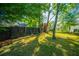 Private backyard with a lush lawn, modern fence, and mature trees providing shade at 3 Lord Ashley Dr, Charleston, SC 29407